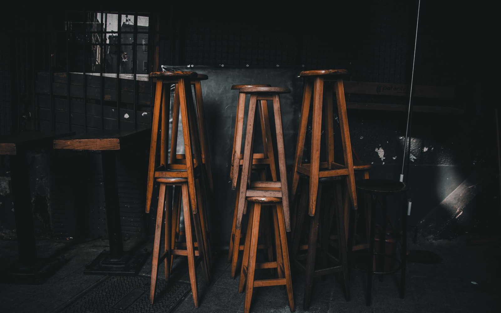 A genuinely old bar interior: focus on accumulated wear — stained rail, overflowing ashtray or old cigarette machine, mismatched stools; not styled, n