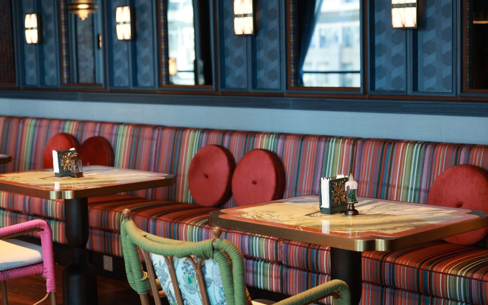 Striped banquette seating with round red cushions and decorative tables in a restaurant booth